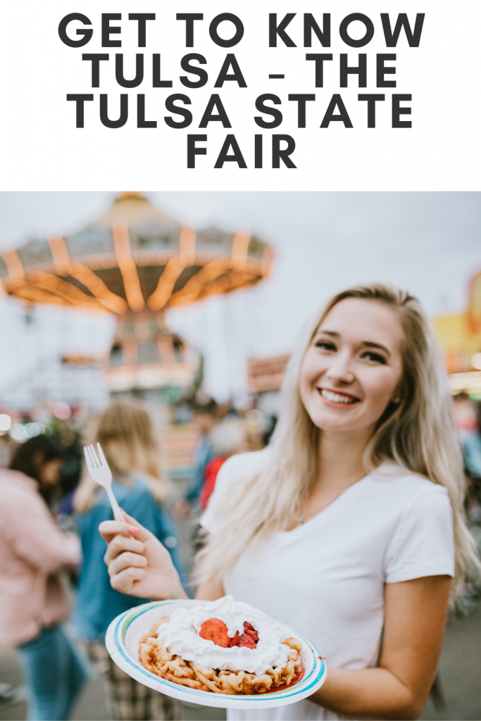 Woman holding a funnel cake in her hand with fair rides in the background.