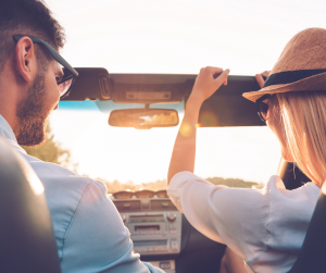 road trip photo showing man and woman in convertible car with sun shining in the windows